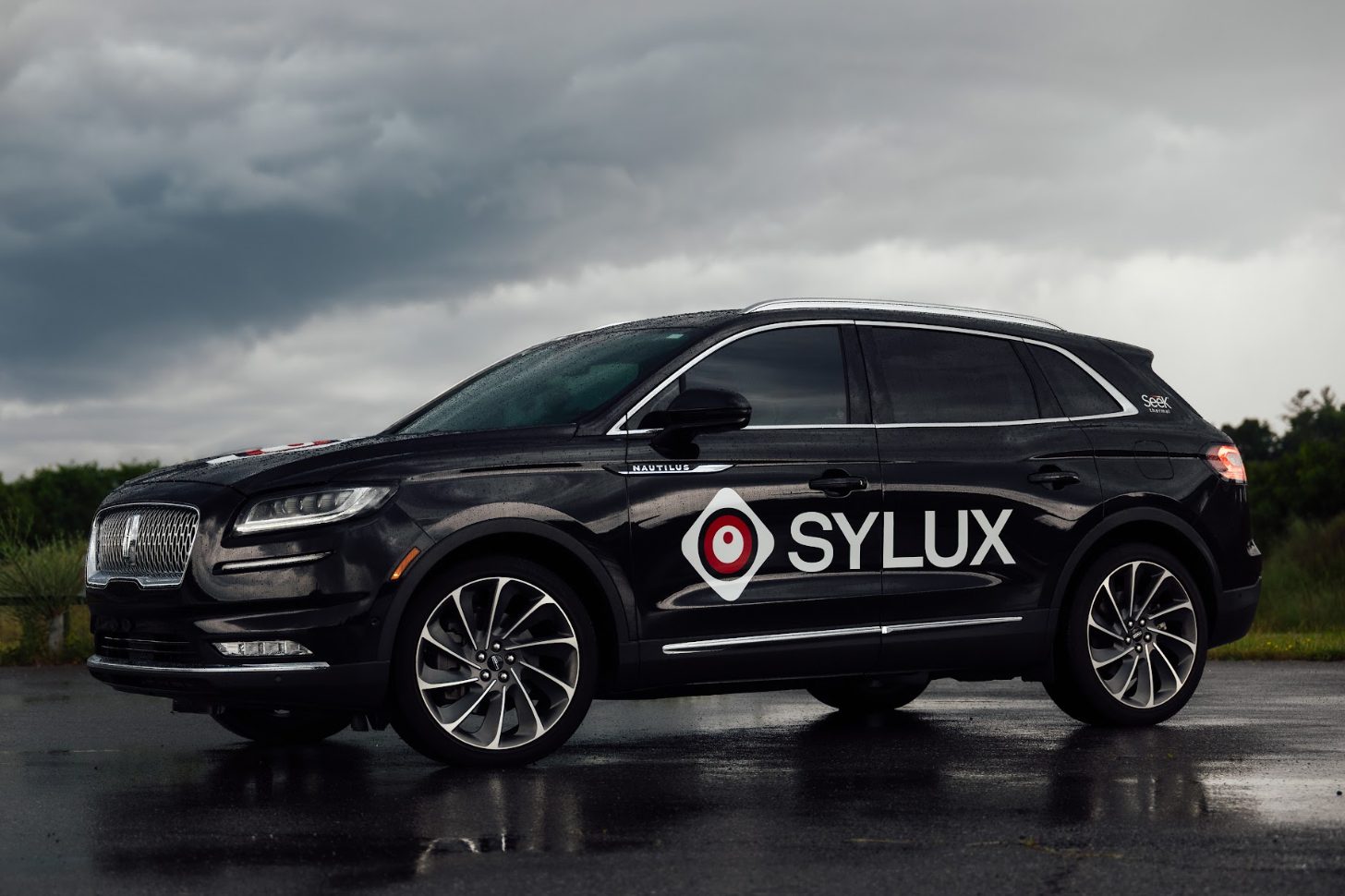 SYLUX-branded test vehicle under storm clouds